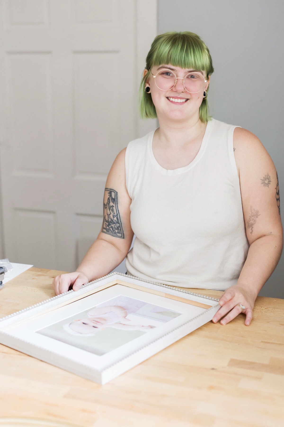 A framer at the workbench with a finished framed portrait